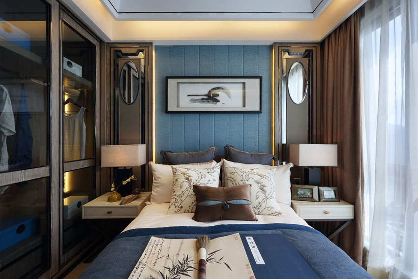 侧卧蓝调的整体搭配凸显典雅，背景墙和床头灯具对称布局，营造出端庄的既视感。