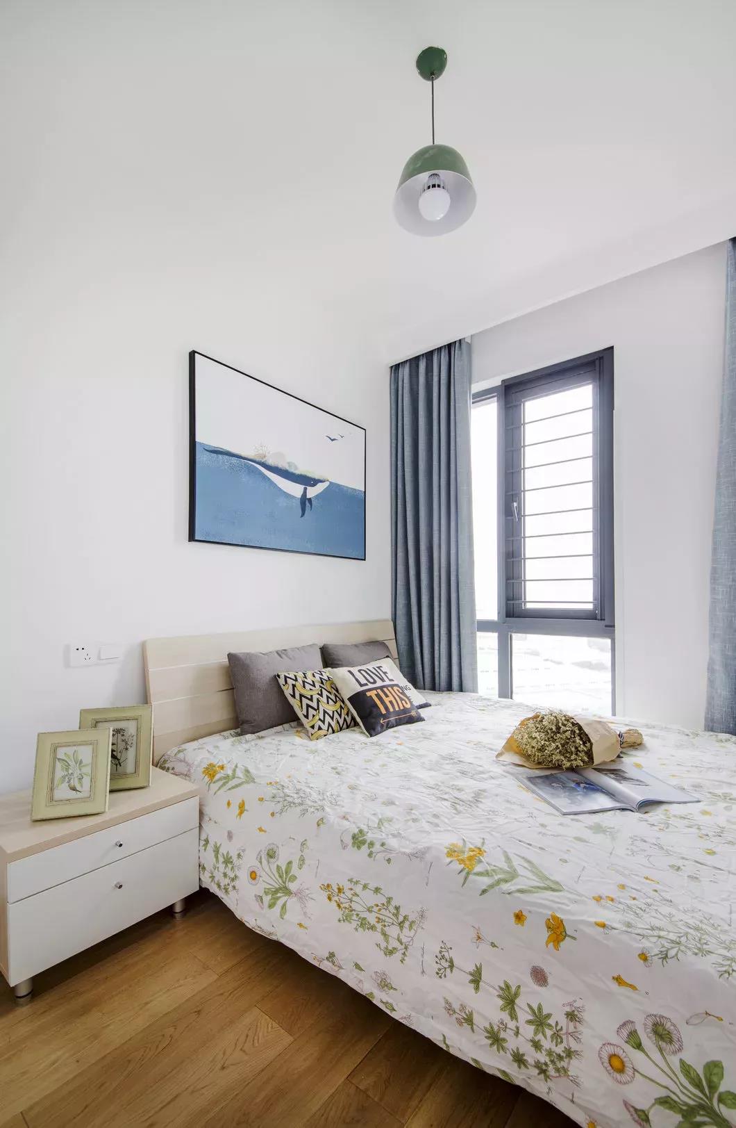 侧卧设计简单，以白色作为主基调，布置花色床单与卡通挂画，让卧室显得充满童趣。