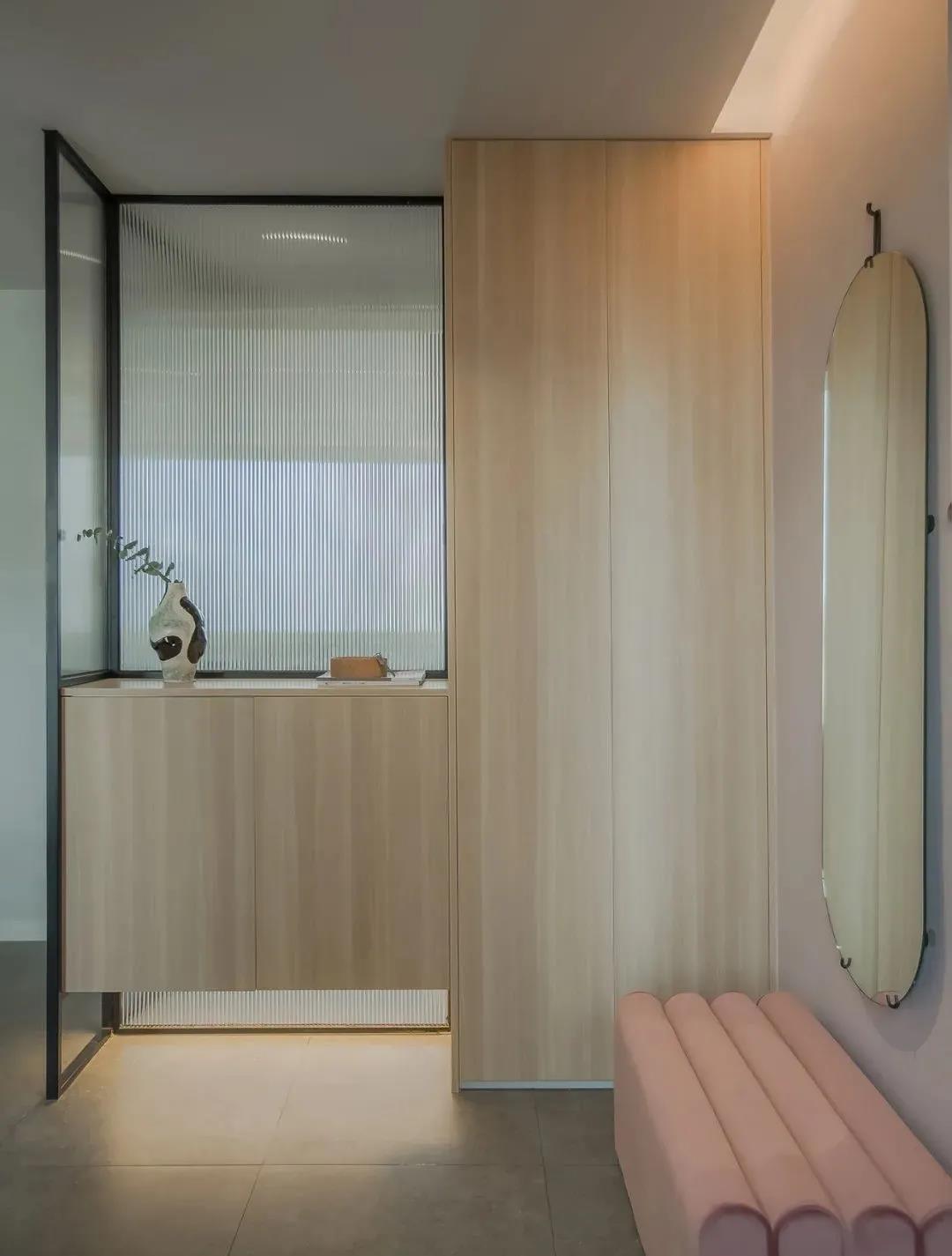 玄关设计的十分淡雅，玄关柜采用高低错落的木色设计，绒质座椅上方放置穿衣镜，实用性高。