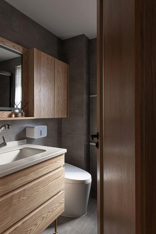 卫生间以木质基调为主，吊柜、洗手池、门、相互融合，提升了视觉整体感。