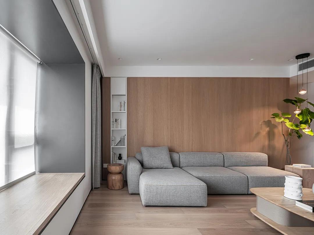 木色背景墙搭配灰色布艺沙发，为客厅营造出一种优雅高档的舒适氛围。