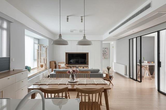 电视墙设计简单，木色餐桌椅搭配白色双吊灯，显得格外的自然清新。