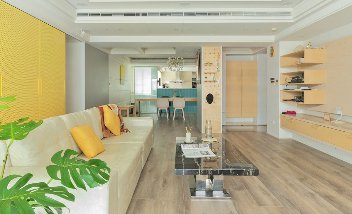 客厅与厨房相连，家具配色上以木色为主机斯奥，融入了黄色背景墙，简洁中又包含着时尚。