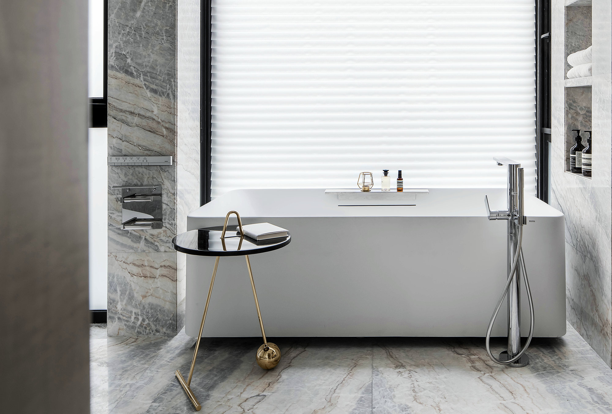 卫生间背景使用大理石铺贴，白色浴缸搭配精致茶几，质感满满，精致无比。