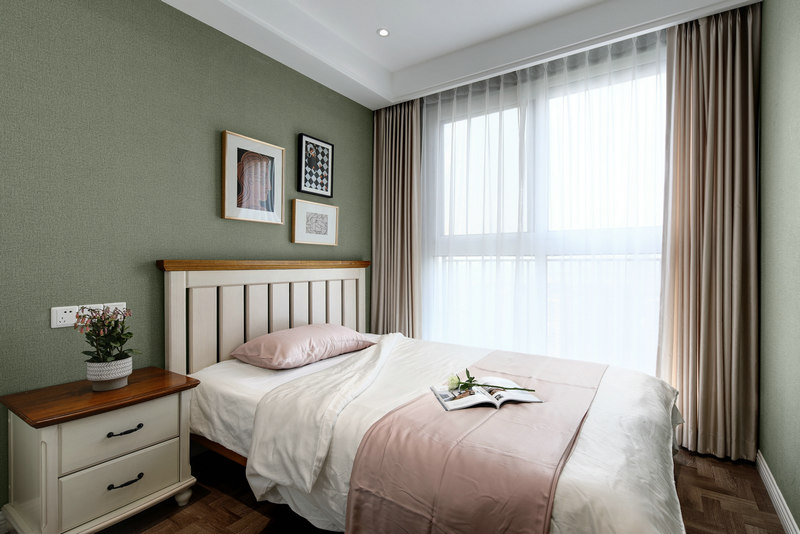 绿色背景墙搭配粉色床品，低饱和度对色运用，营造出温馨舒适的氛围。