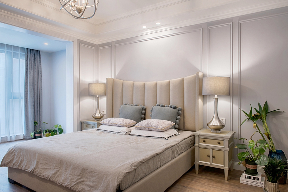 卧室背景墙使用白色护墙板打造，精致特别，弧度床头在空间中气质十足，整体氛围静谧安详。
