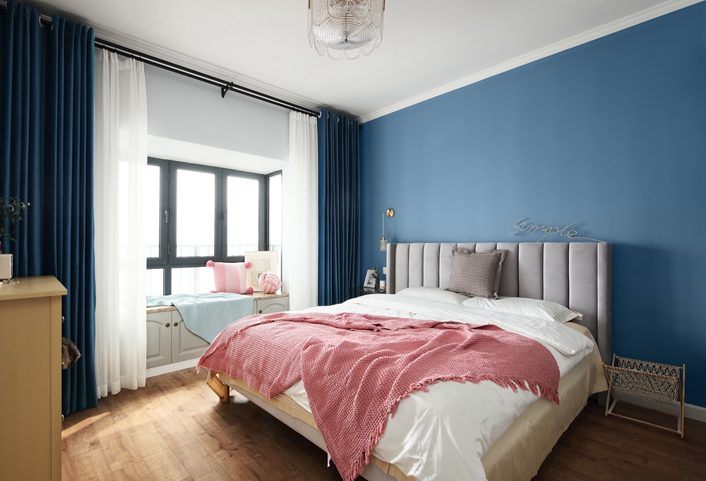 蓝色背景墙与粉色床品形成鲜明对比，亦增强了侧卧空间的治愈感。