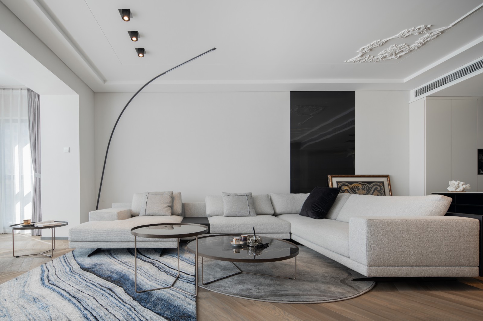 客厅以白色为主基调，L型布艺沙发凸显聚拢感，局部黑色点缀，提升素雅感。