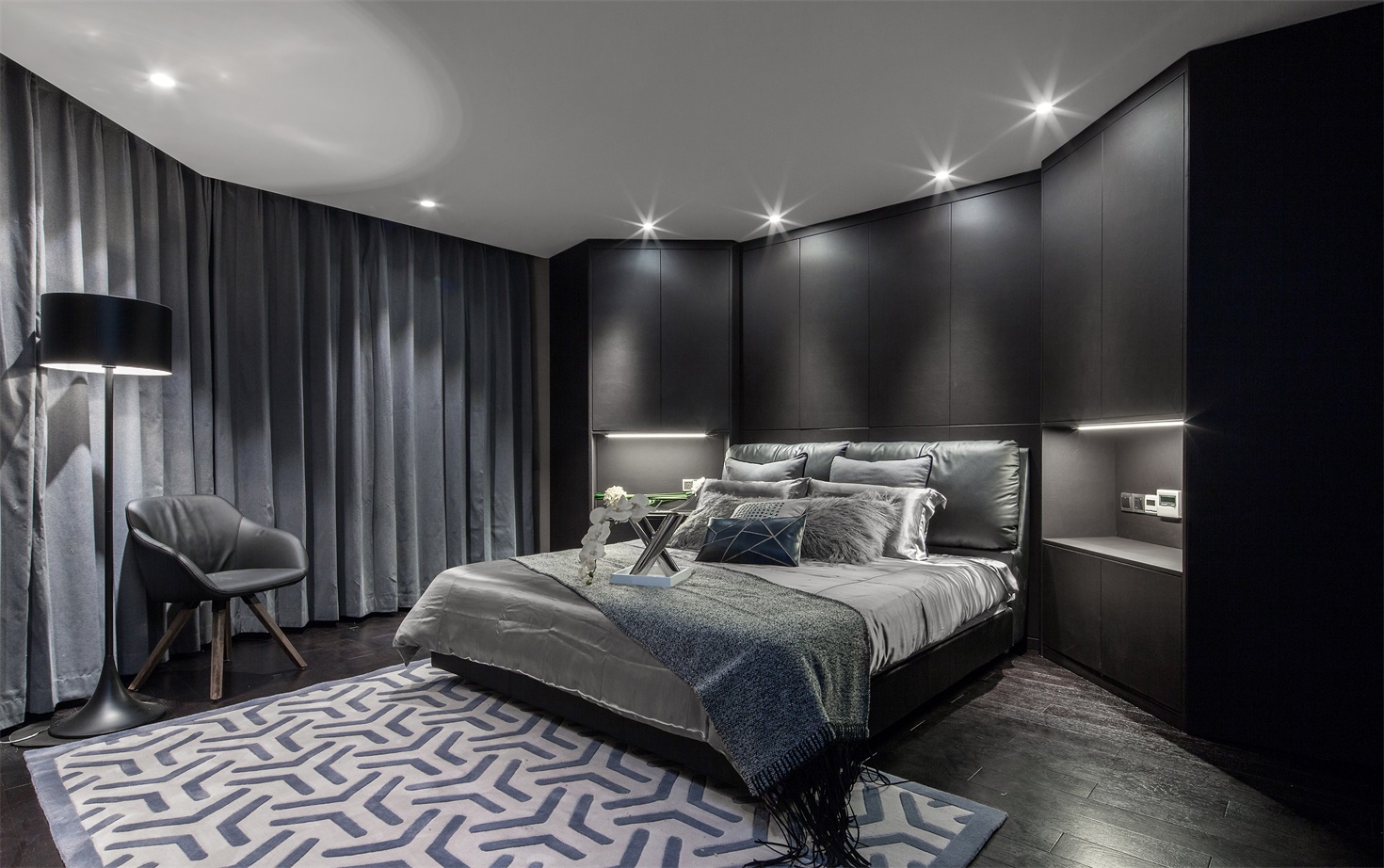 卧室设计刚柔并济，吊顶射灯缓解黑色背景墙带来的高冷之感，营造出雅致大气的空间感。