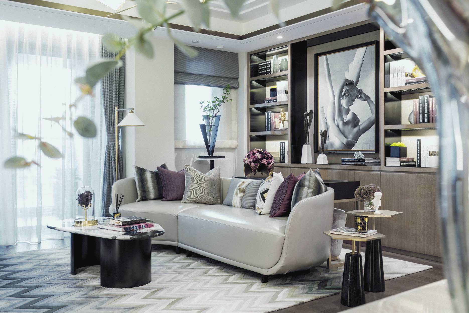 客厅沙发造型简洁，背景书柜线条流畅，整体选用轻奢风中常见的气质色调打造。