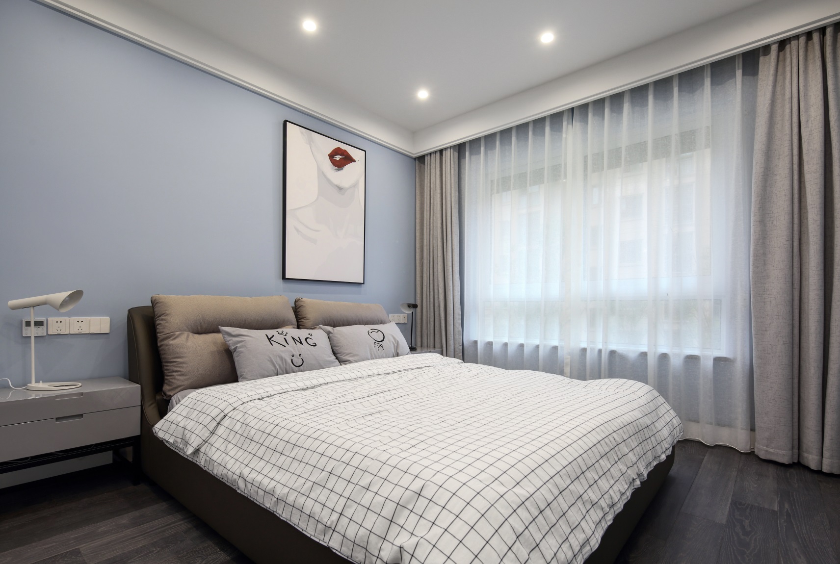 小卧室采用无主灯设计，筒灯增加了空间的氛围感，蓝色背景墙搭配灰白色床饰，强化了都市感。