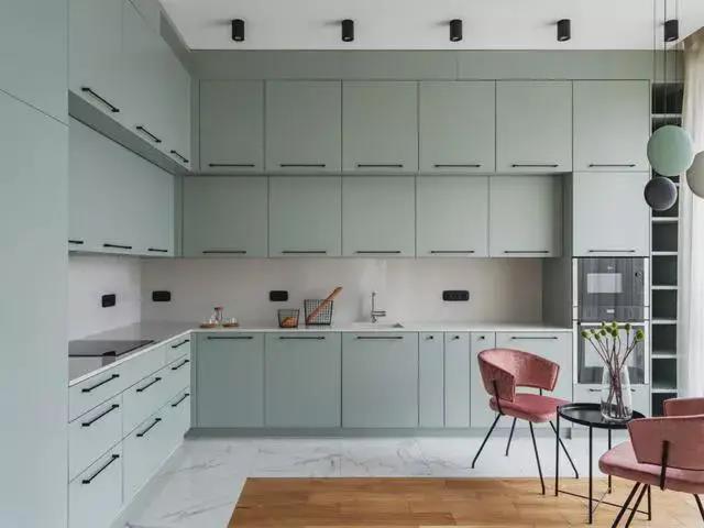 L型橱柜操作台围绕着餐桌布置，浅蓝色橱柜层次分明，让烹饪氛围更加轻松闲适。