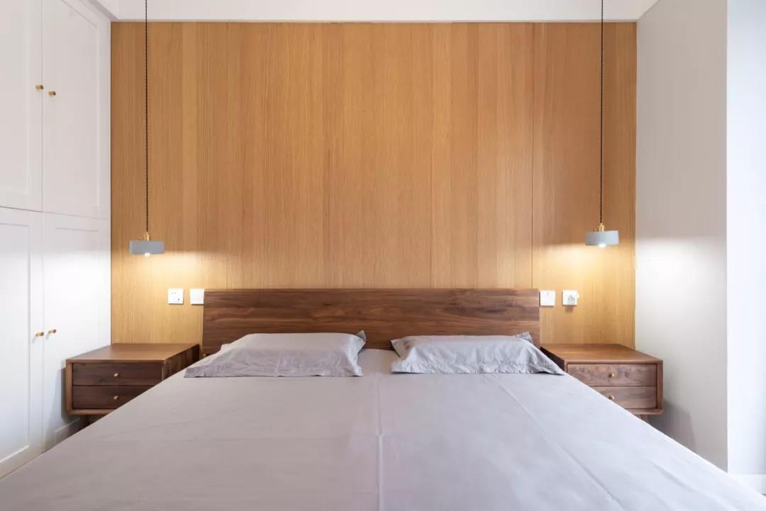 木质床头搭配灰色的床铺，床头柜上点缀了垂吊灯具，体现出空间的日系气息。