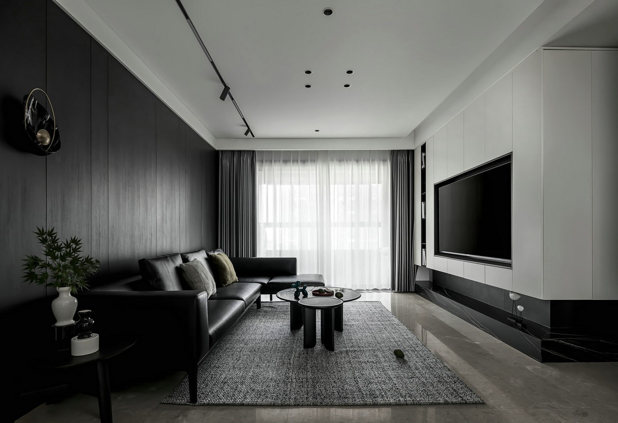 客厅以黑白色为主题，皮质沙发搭配黑色背景墙，呈现哑光质感，符合简约的装修理念。