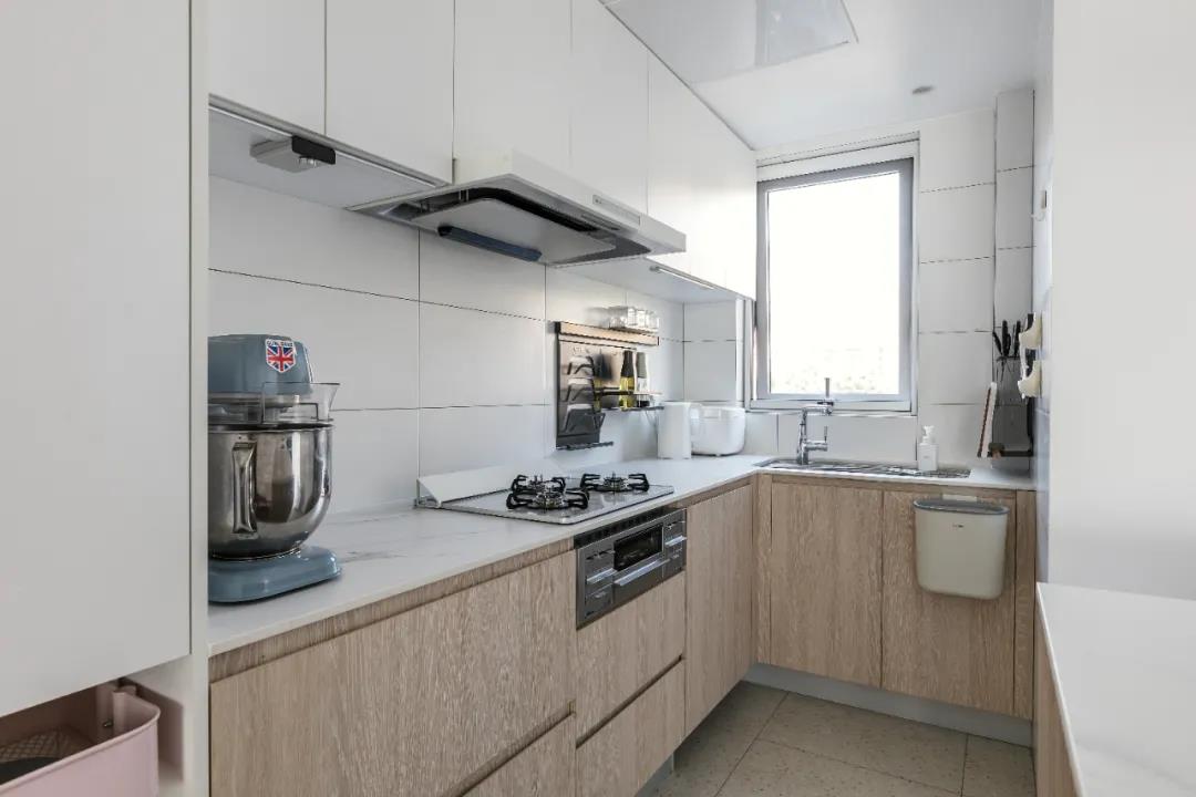 厨房设U字型设计，白色大理石台面和木色橱柜经典搭配，清洗区、烹饪区分区明显。
