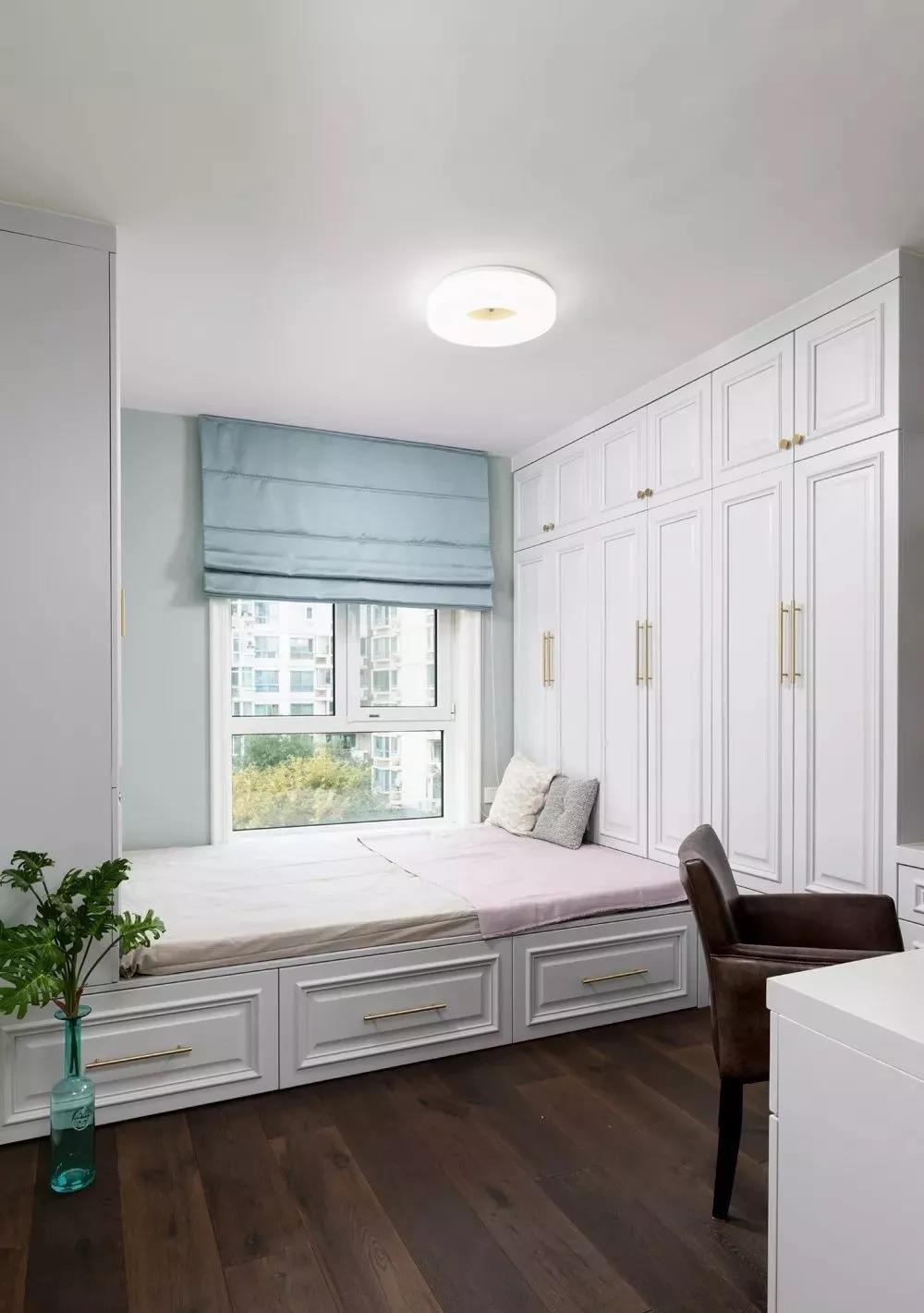 白色地台床、衣柜、一体化设计，在整体白色的基调上，蓝色窗帘成为点缀。