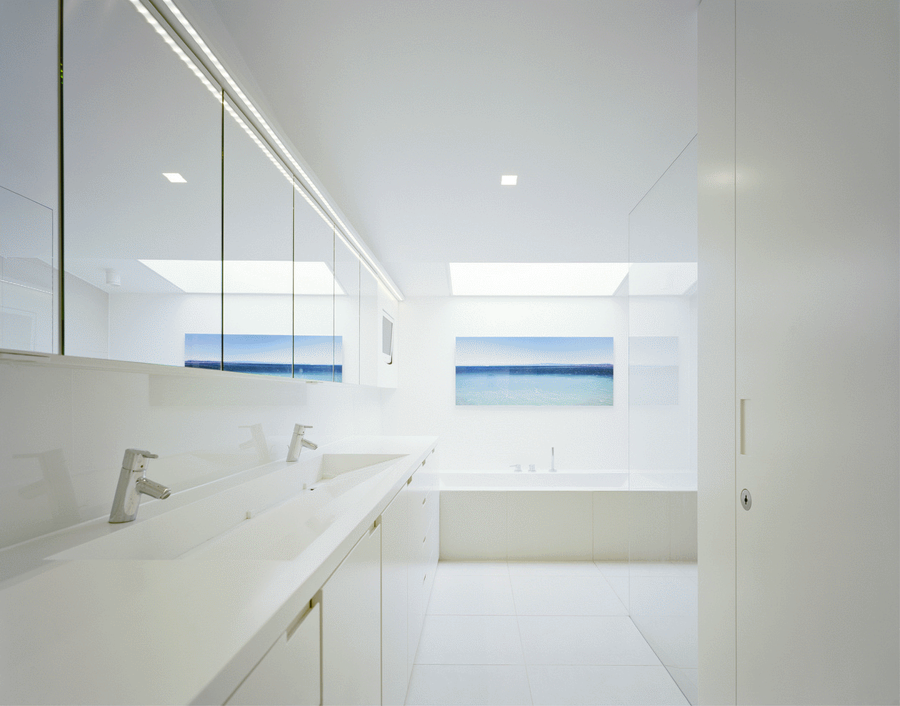 卫生间以白色为基调，视觉效果宽敞明亮，局部蓝色装饰画打造出空间意境。