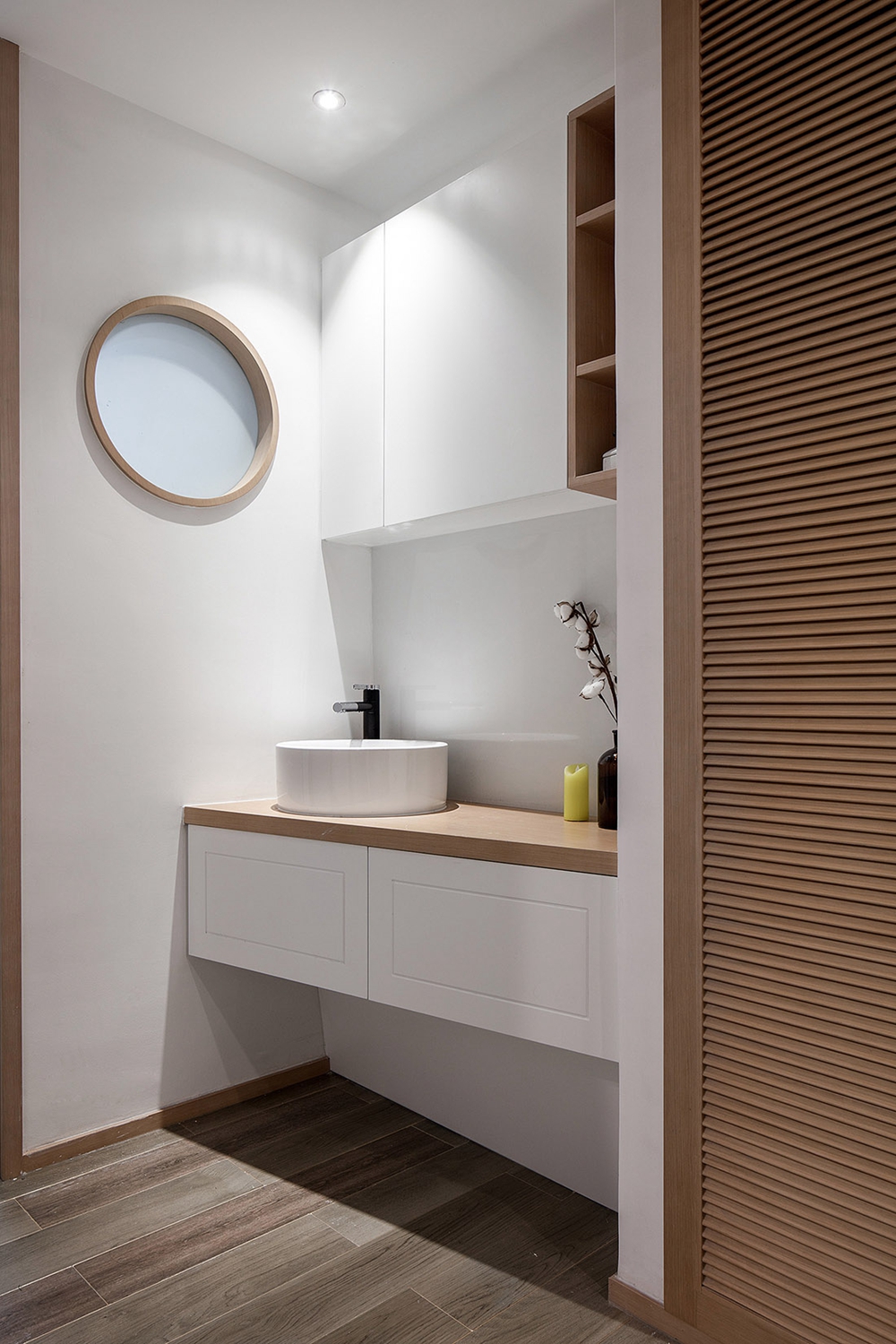洗手台以木色和白色相互融合设计，在照明的搭配下，令空间展现出清新与暖意。