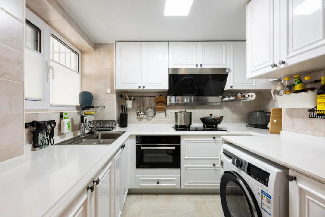厨房定制白色橱柜，操作台面布置各式各样的厨具，让空间充满生活气息。