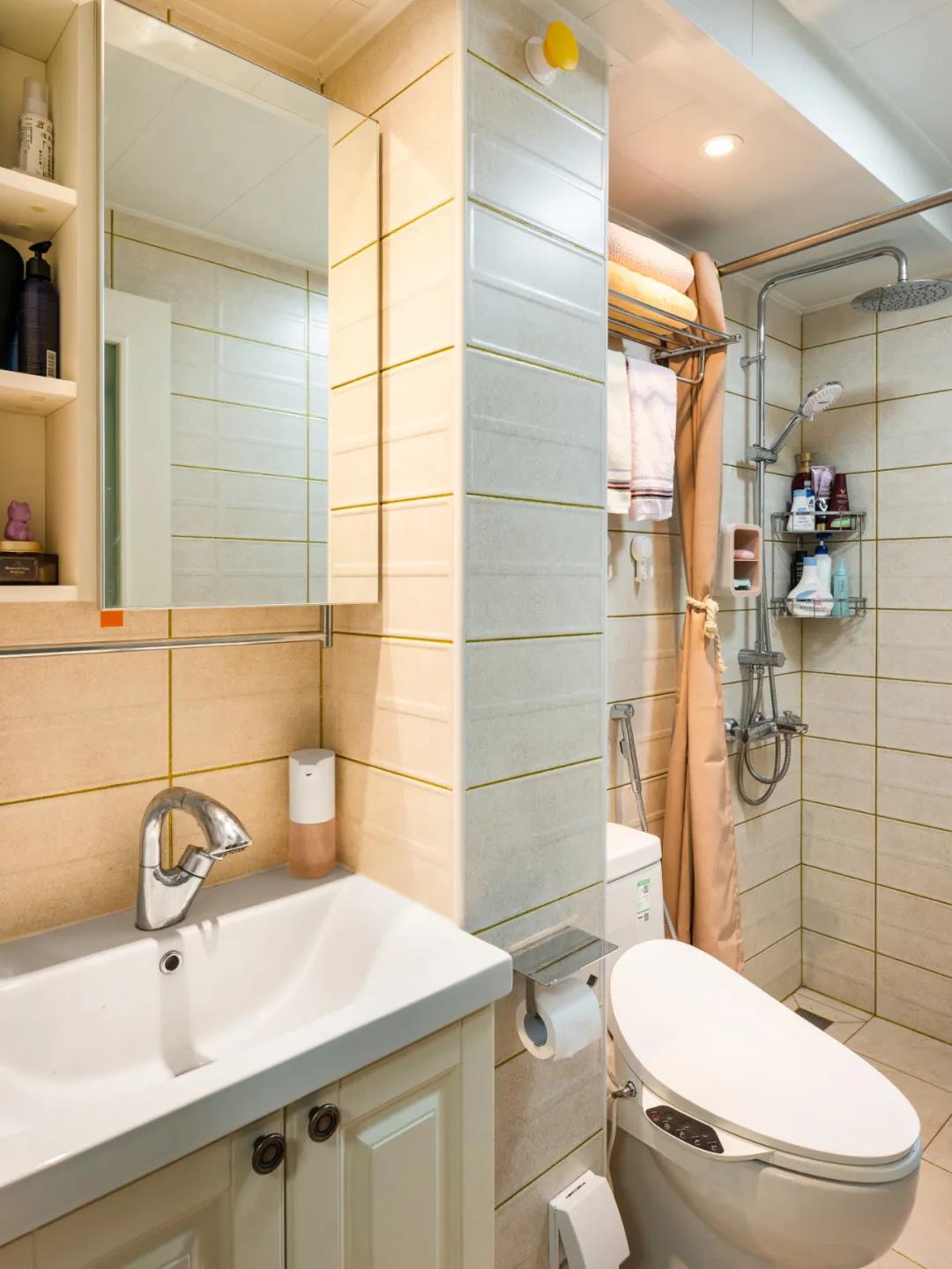 卫生间以米色为主调，整个空间更显温馨，局部使用浴帘进行干湿分离。