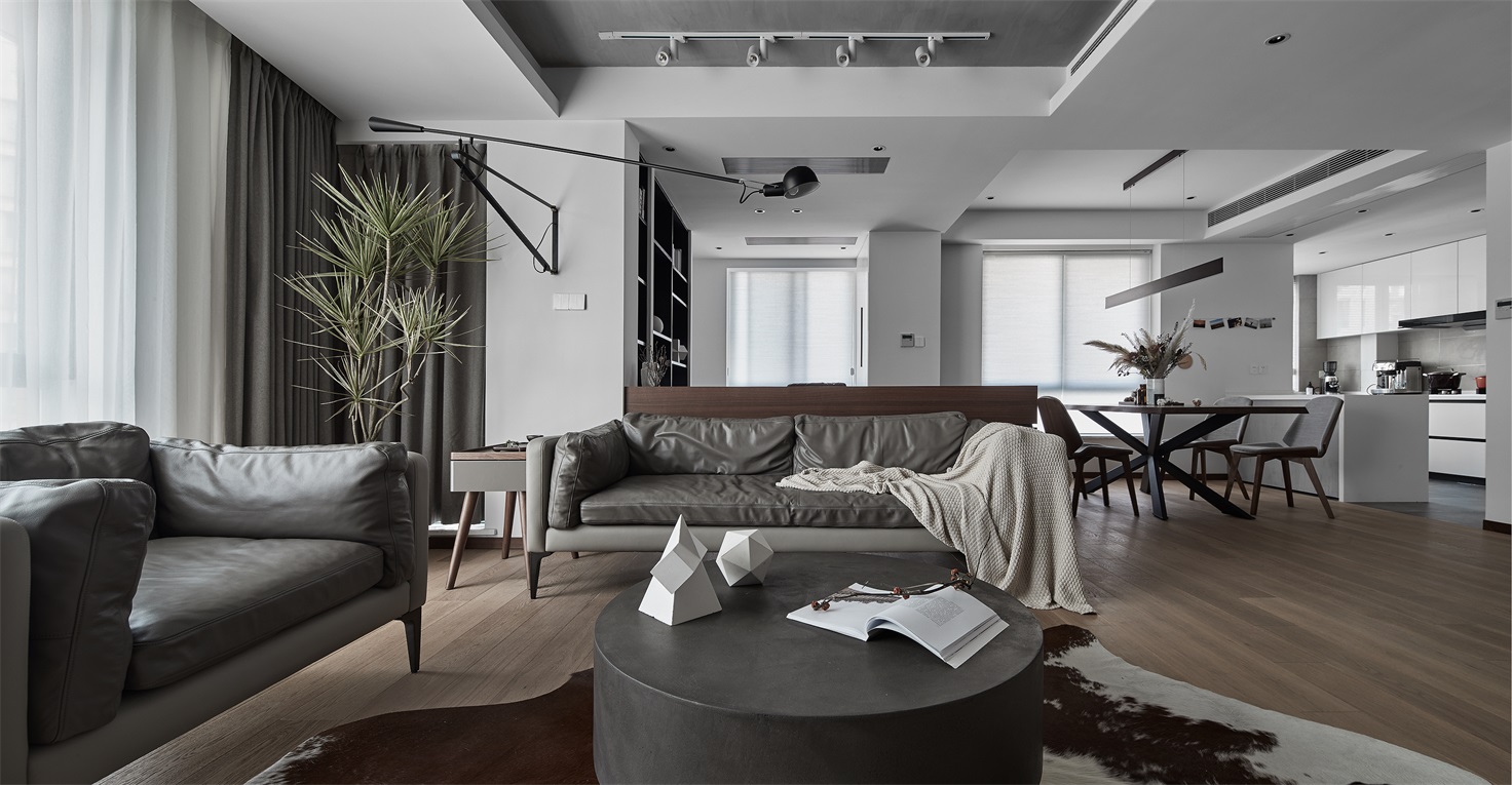 客厅配色较为硬朗，咖色皮质沙发很好的提升了空间格调，一侧绿植点缀，看上去现代感十足。