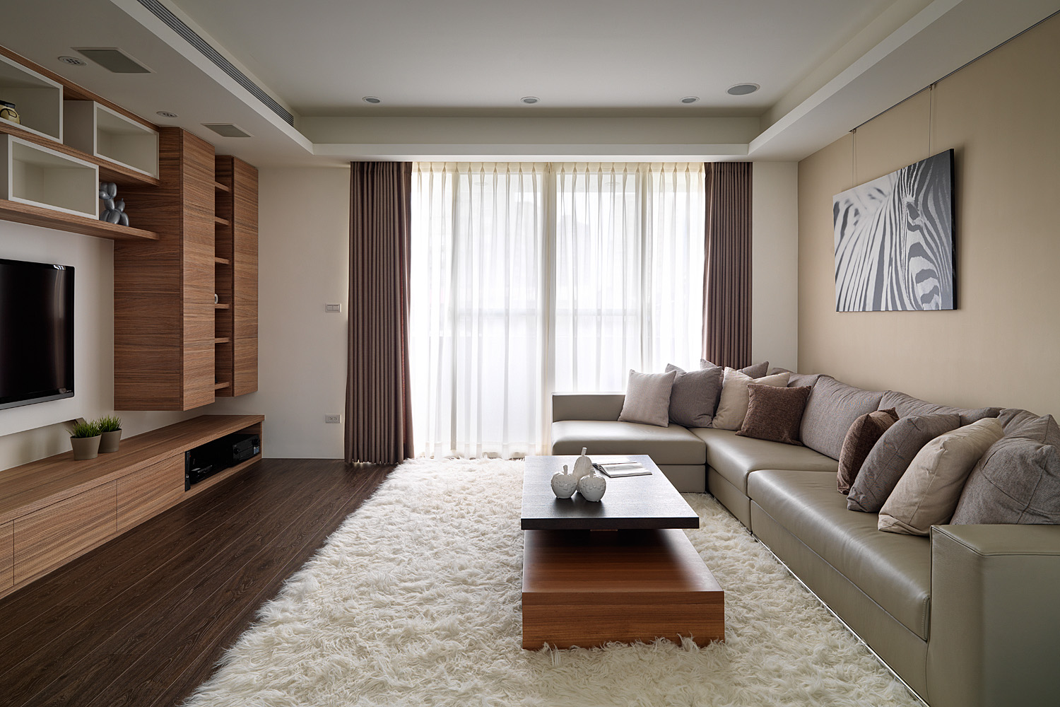 米色沙发与明亮的背景色调形成制衡，白色地毯填补了客厅的空白。