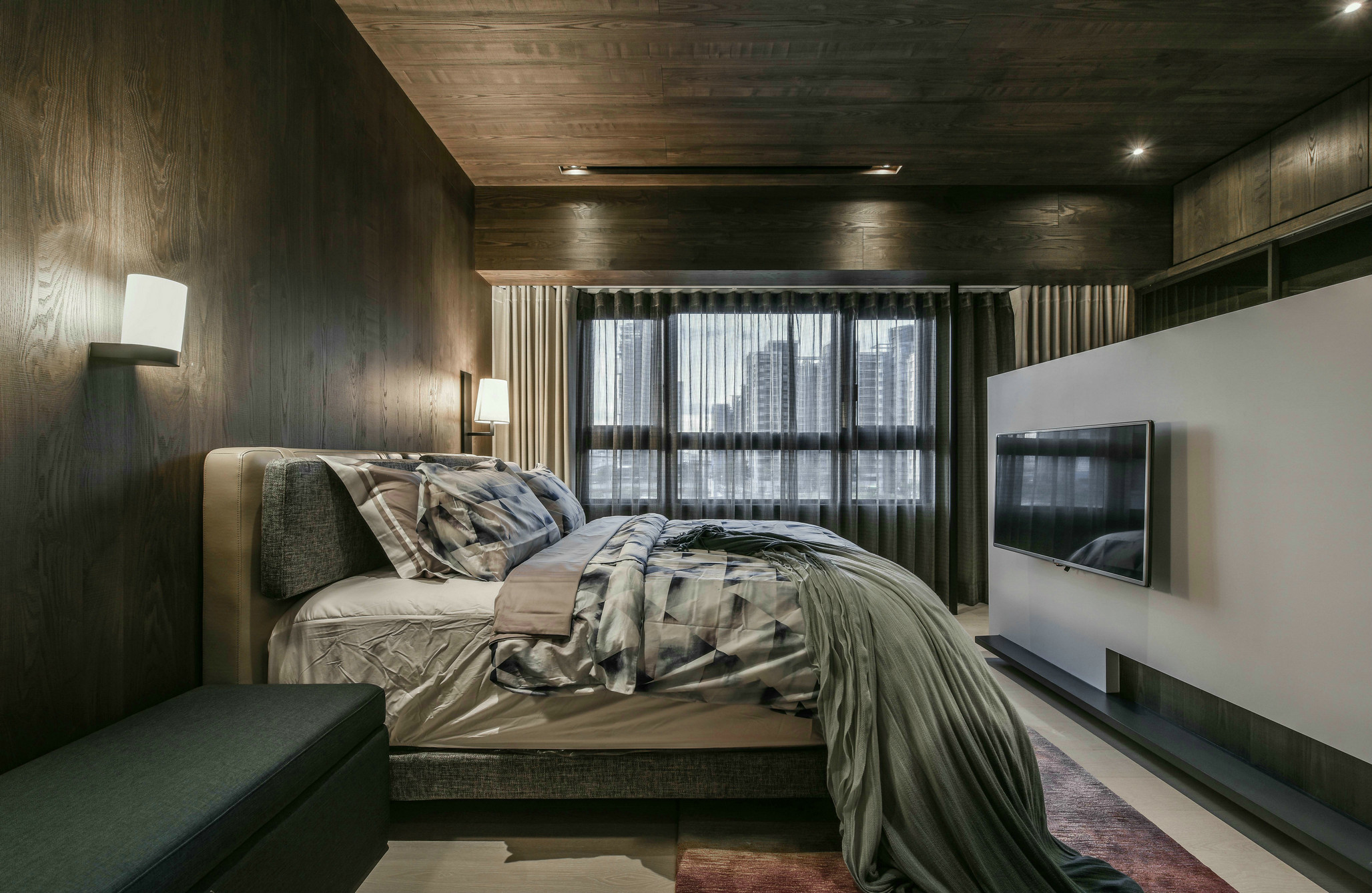 主卧采用无主灯设计，顶面与墙面都使用了木质元素铺贴，增强了空间的设计感。